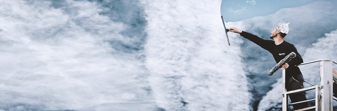 Das Foto zeigt einen Mann mit Aluhut, der mit einem Fensterreiniger Chemtrails beiseite schiebt.